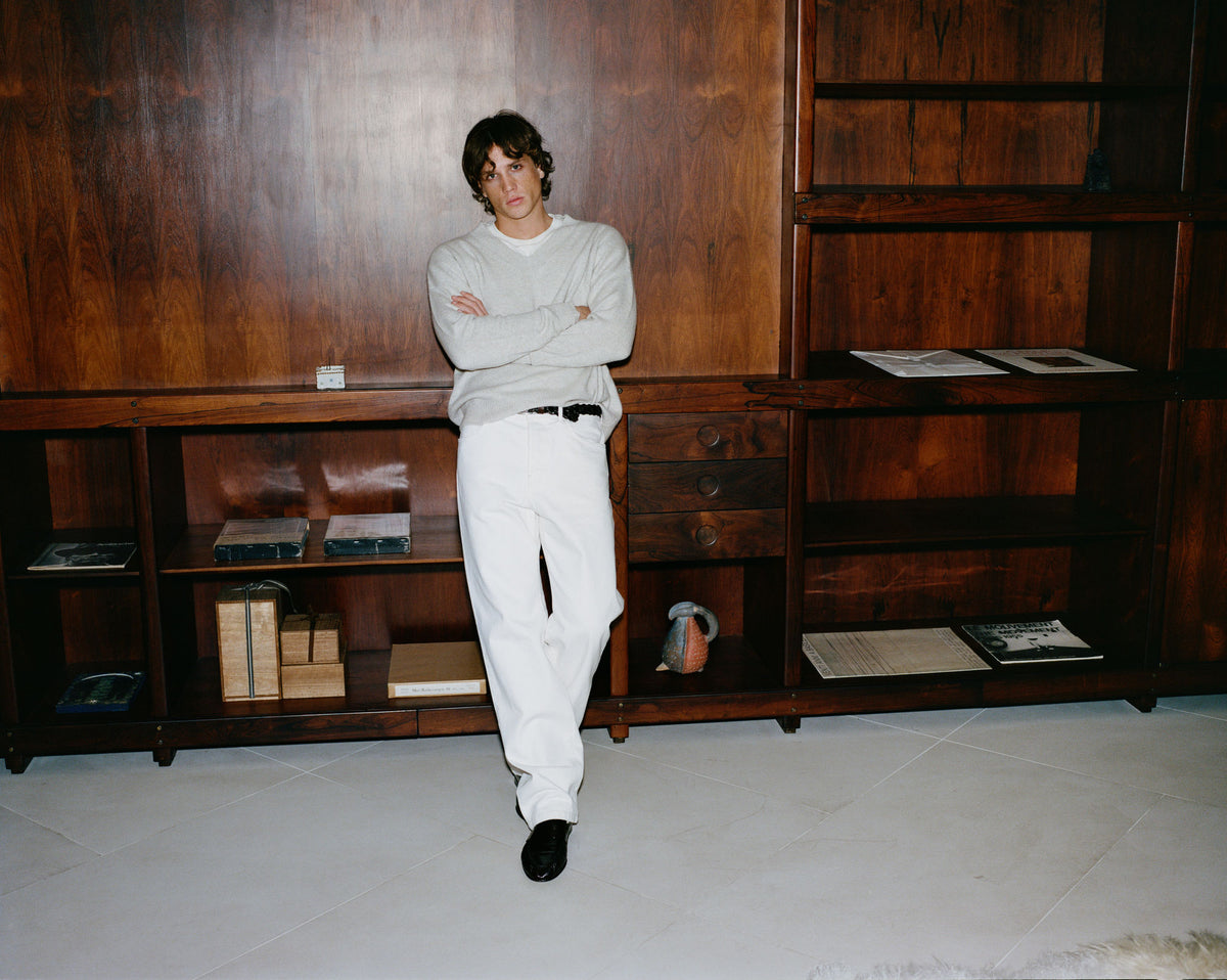 Model in Lee Sweater over Gianni T-Shirt with Tyler Wide Jean beside wood cabinetry